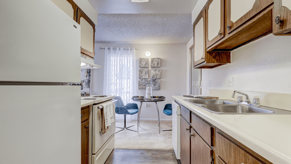 a kitchen with white appliances and wooden cabinets and a dining room with a table