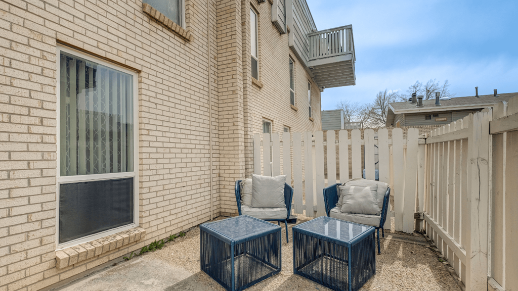 a backyard with two chairs and a fence and a balcony