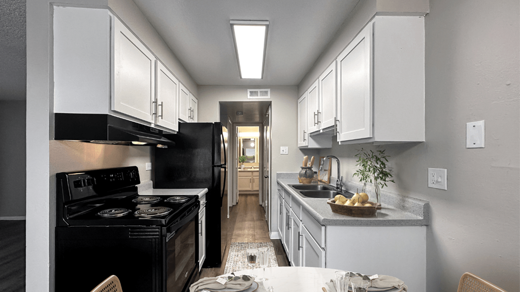 a kitchen with white cabinets and black appliances and a table