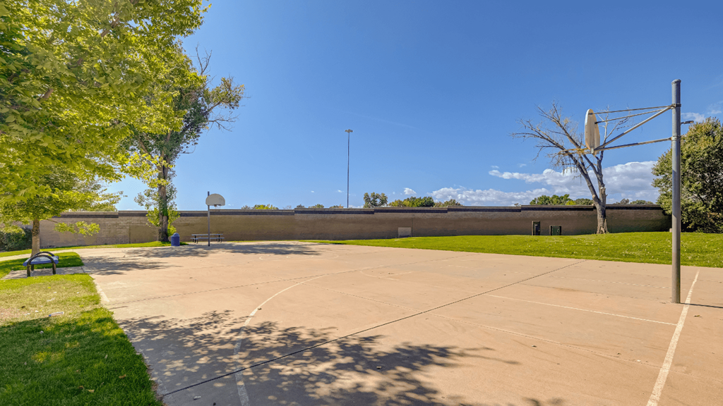 a basketball court in a park with a blue sky