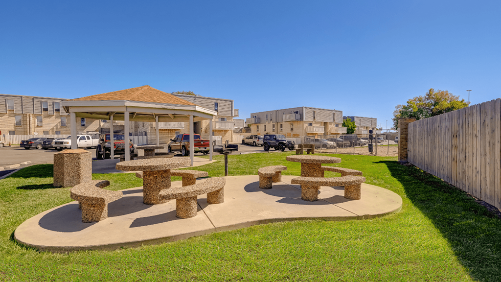 a group of stone picnic tables and benches in a park