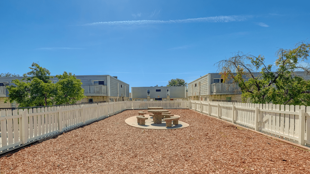 a fenced in area with a fire pit and a white fence