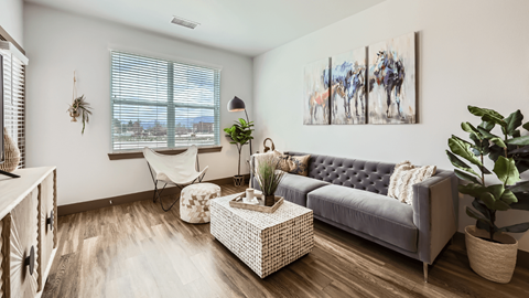 A living room with a grey couch, a white wicker coffee table, and a painting of a horse on the wall.