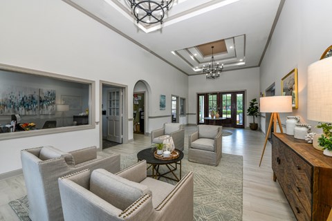 A well-lit, spacious living room with a skylight, a grey sofa set, a wooden sideboard, and a large painting on the wall.