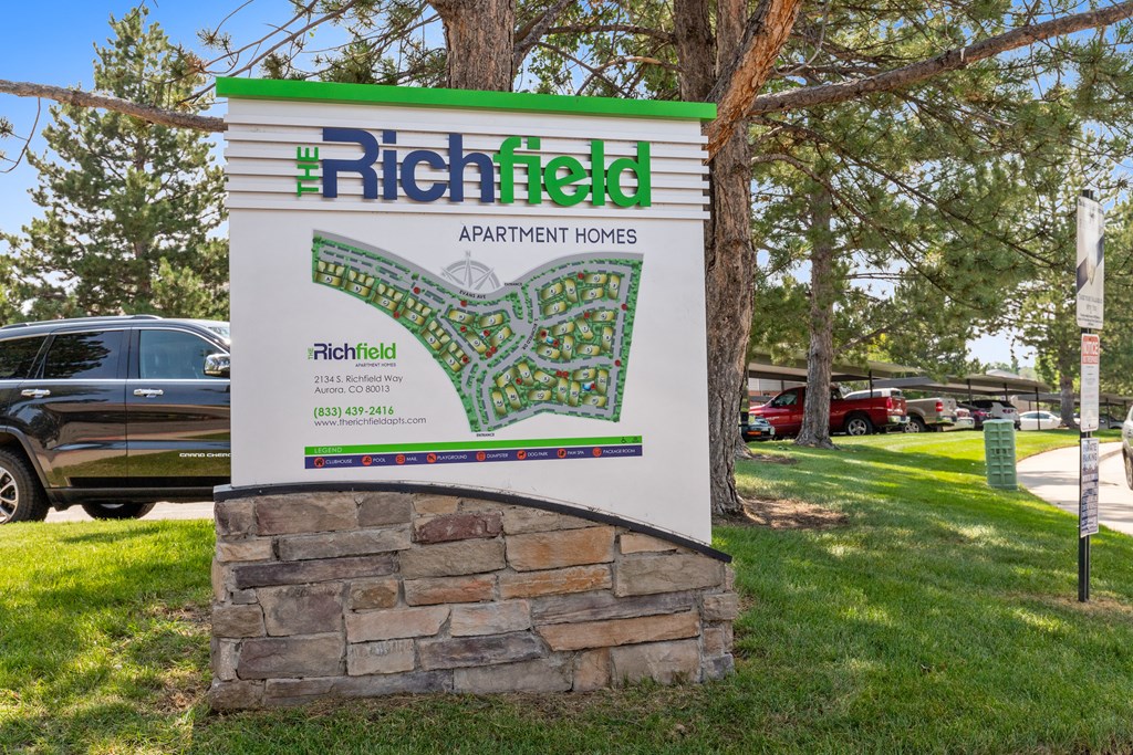 a sign for the richfield apartment homes parking lot in front of a tree