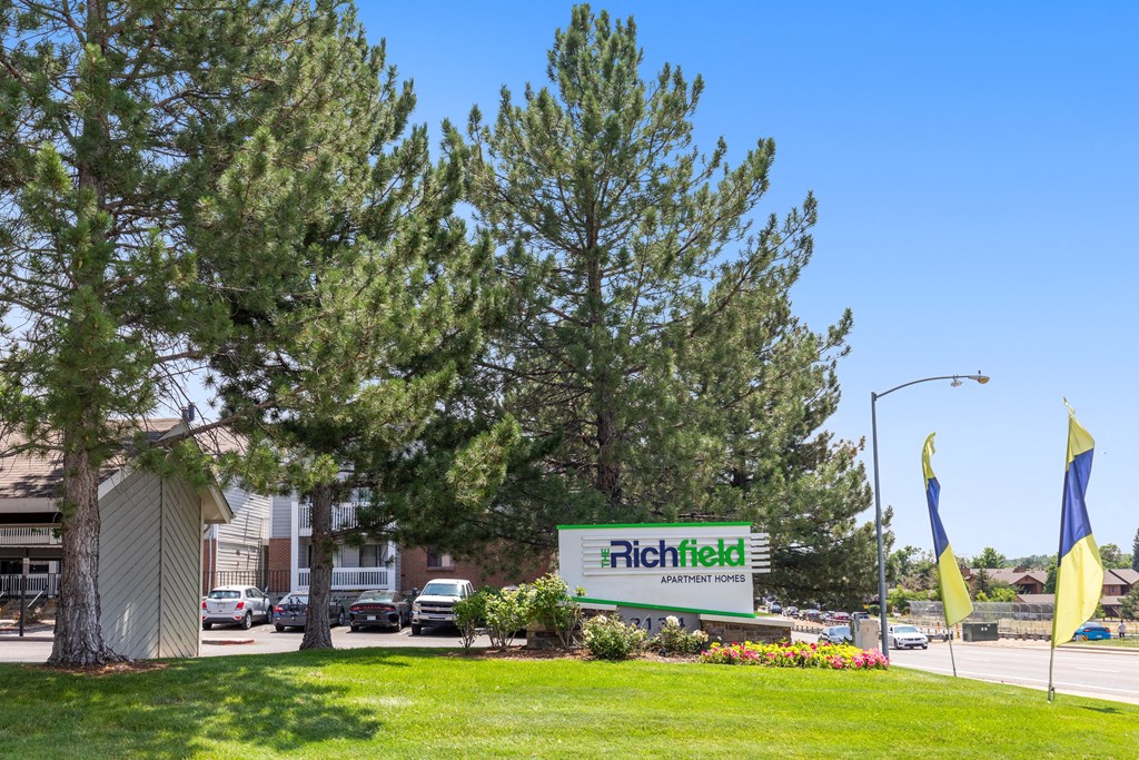 a city street with a hotel sign and a green lawn with trees