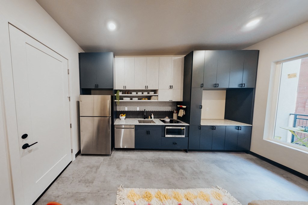 a kitchen with black and white cabinets and stainless steel appliances