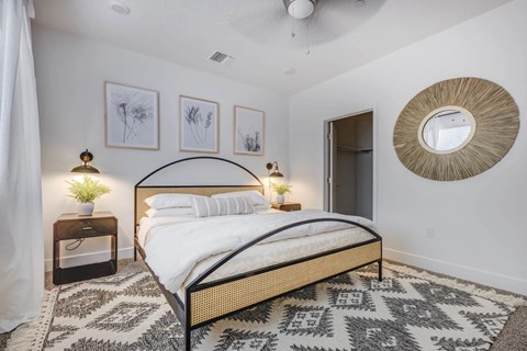 A bedroom with a large bed and a round mirror on the wall.