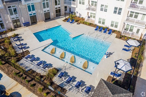 A large swimming pool surrounded by lounge chairs and umbrellas.
