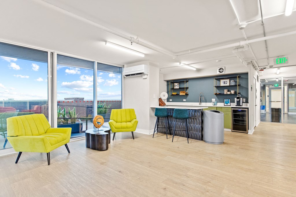 a living room with yellow chairs and a kitchen with a large window