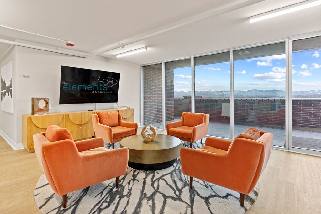 a living room with orange chairs and a television    and a large window