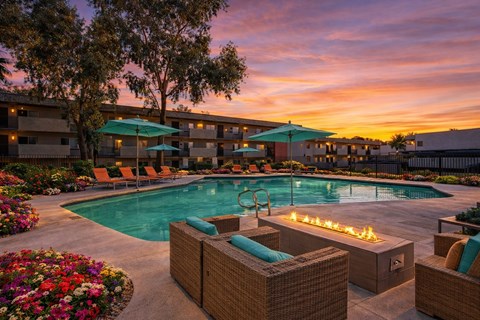 A pool surrounded by wicker chairs and umbrellas.