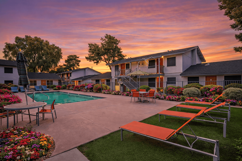 A sunset view of a poolside area with a table and chairs.