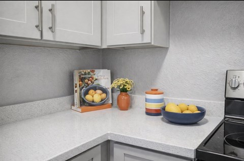 A kitchen counter with a bowl of lemons, a vase with flowers, and a book about fruit.