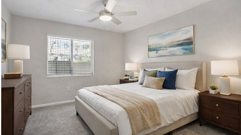A bedroom with a large bed, a ceiling fan, and a painting on the wall.