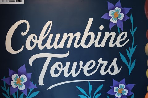 Columbine Towers sign with flowers on a dark background.