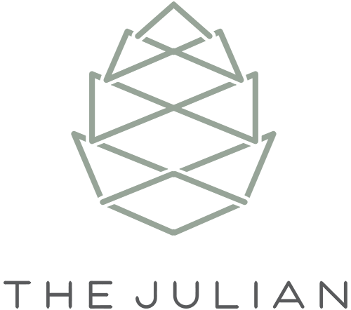 A logo with a geometric pine cone design and the text "THE JULIAN" below it.