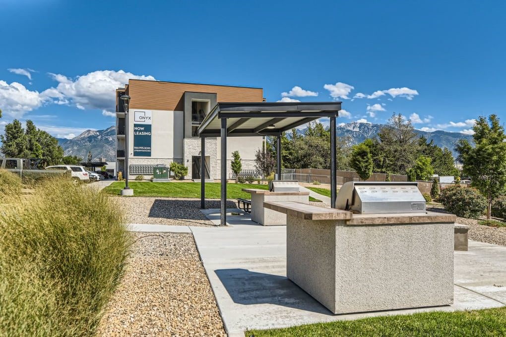 a picnic area with a grill and a building with mountains in the background