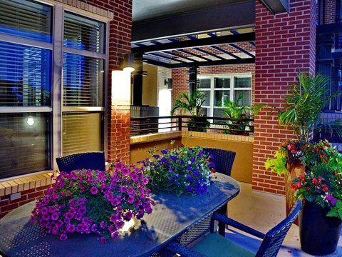 A table with a flower arrangement on it sits on a patio.