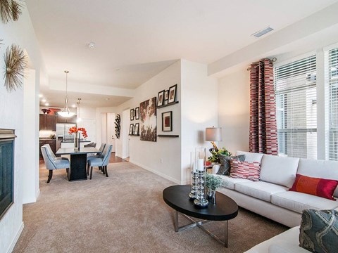 A living room with a white couch, a black coffee table, and a dining table with chairs.