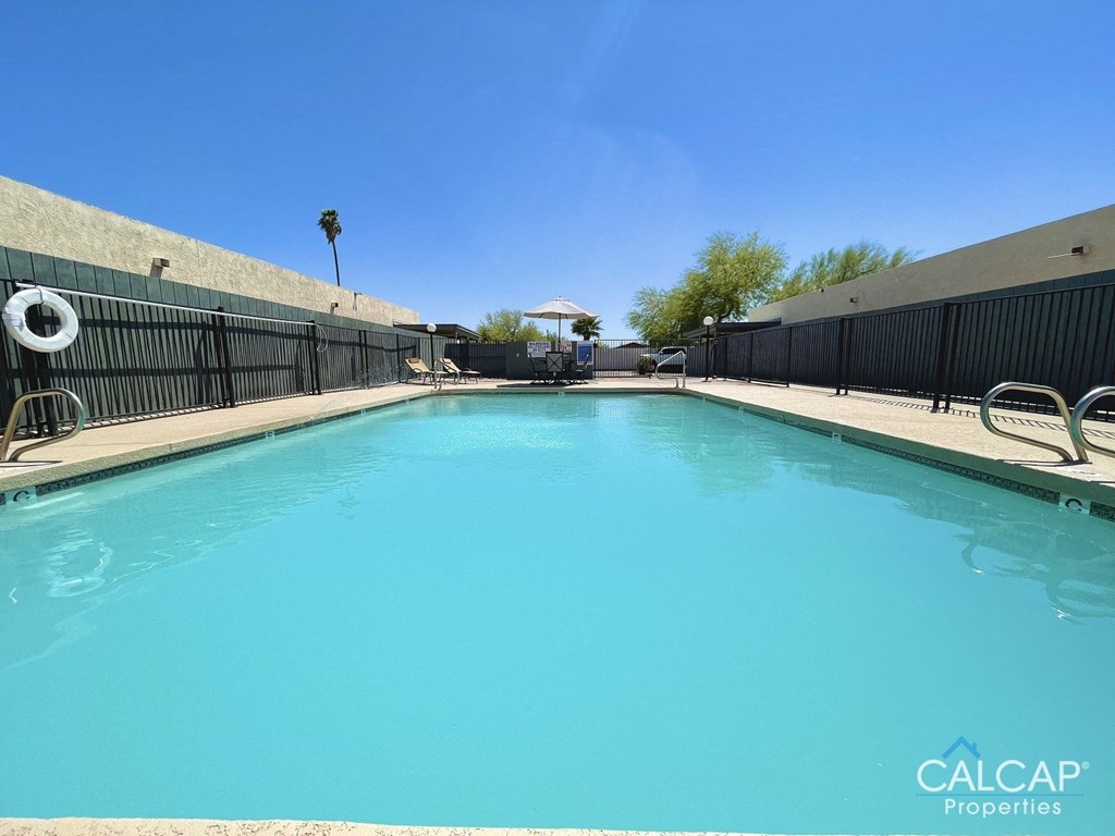 A pool with a blue tinted water and a white inflatable ring floating in it.