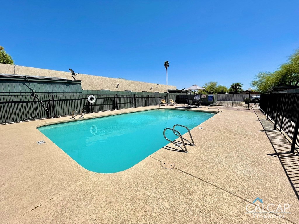 A pool with a blue tinted water and a black fence around it.