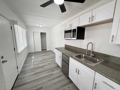 A kitchen with white cabinets and a grey countertop.