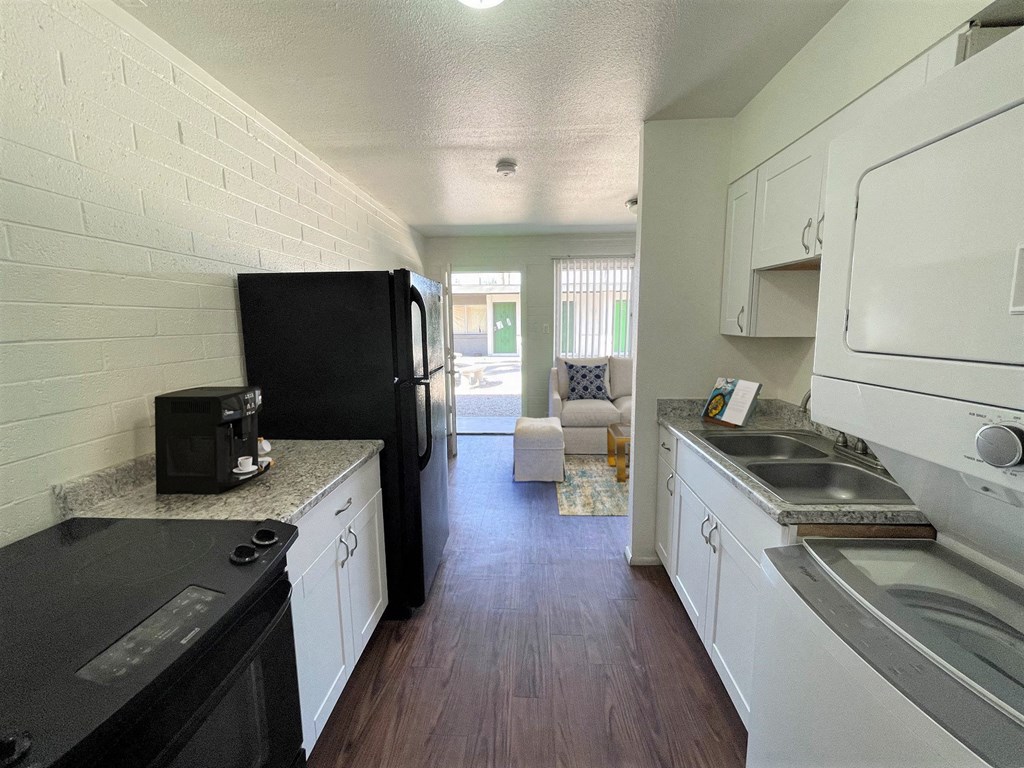 A black fridge and microwave in a kitchen with white cabinets.