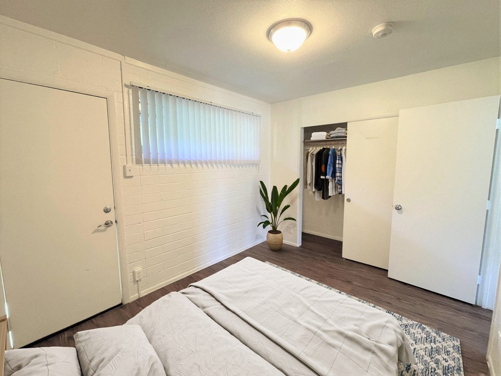 A bedroom with a bed, pillows, and a plant.