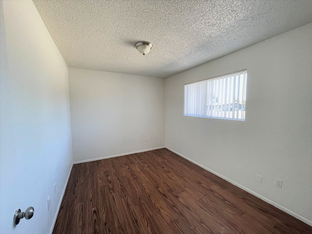 A room with a wooden floor and a window with blinds.