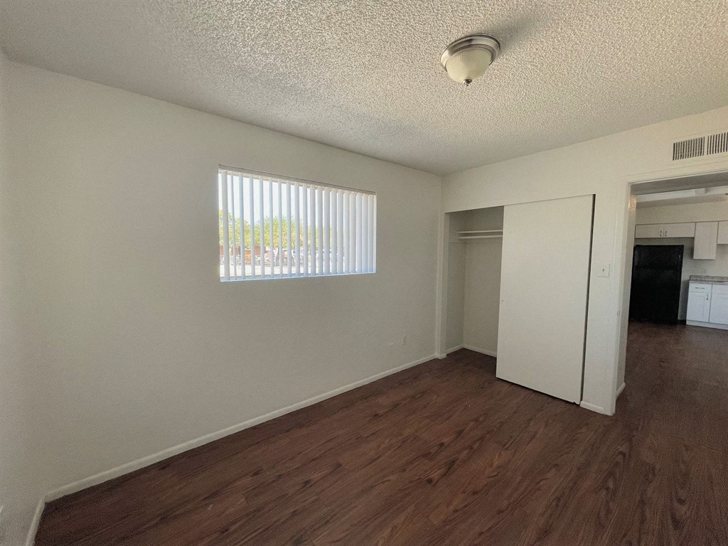 A room with wooden floors and a window with blinds.