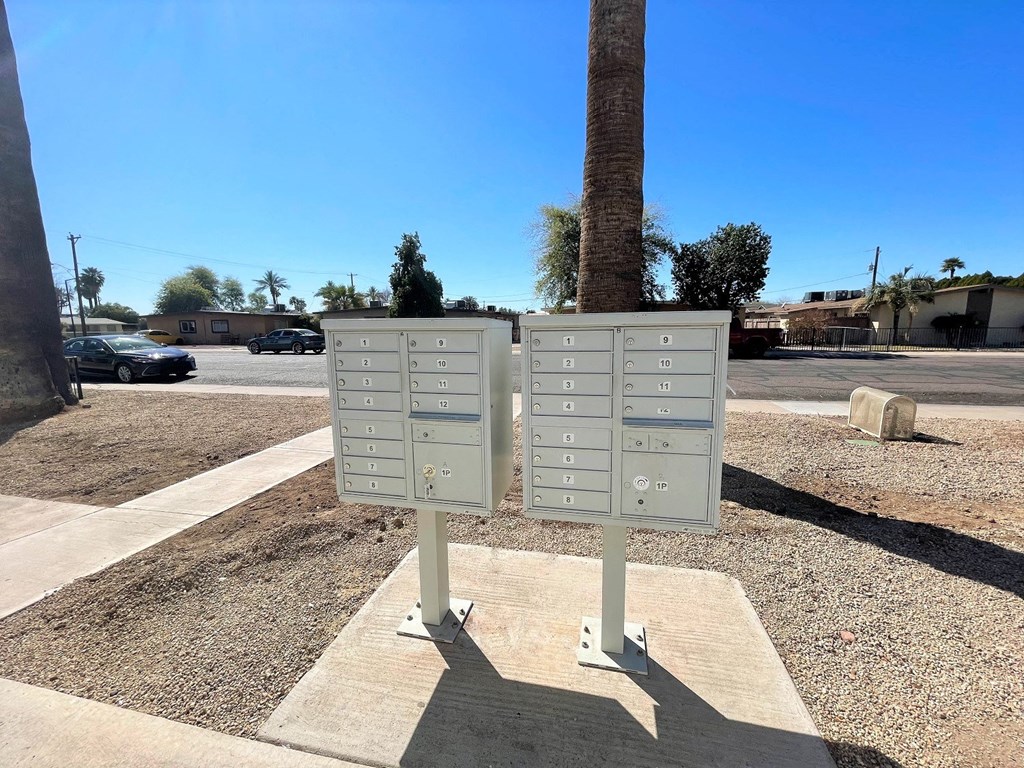 A sign with multiple buttons is in the foreground with a clear blue sky and some trees in the background.
