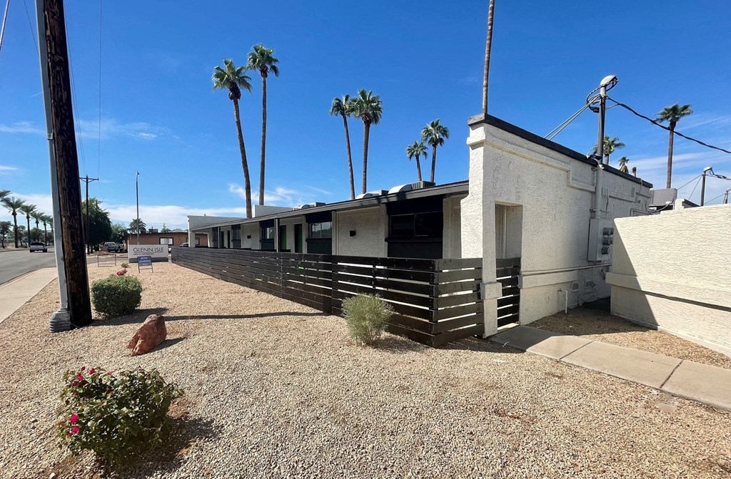 A building with a sign in front of it and palm trees in the background.