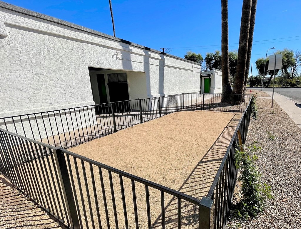 A white building with a black fence and a green door.