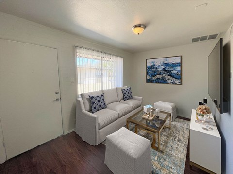 A living room with a white couch, a coffee table, and a painting on the wall.
