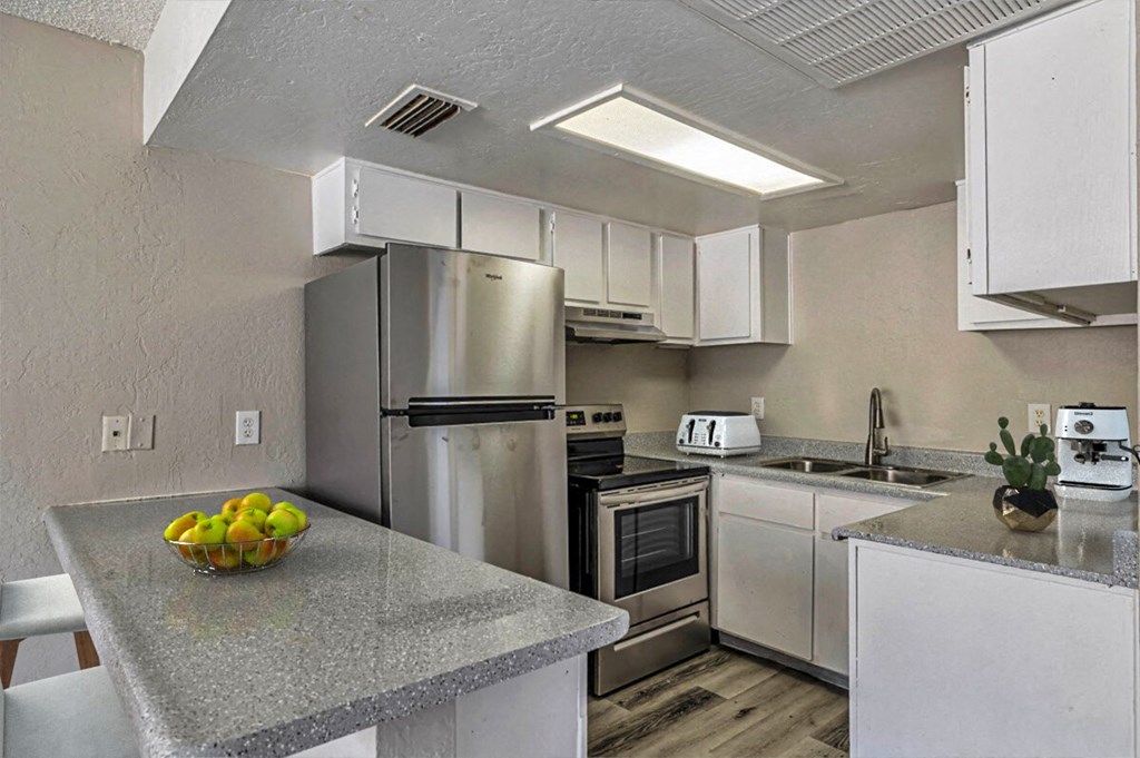 A kitchen with a granite countertop and stainless steel appliances.