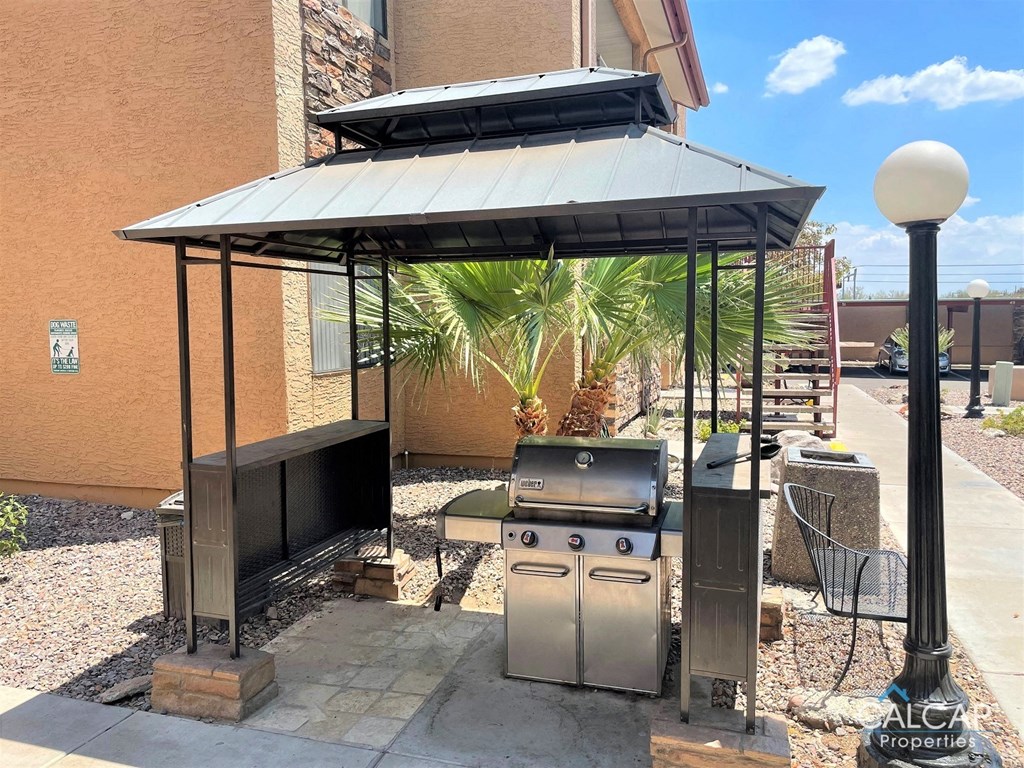 A patio with a grill and a table under a roof.