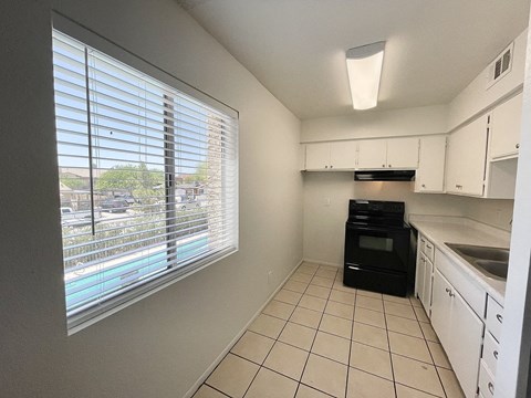 A kitchen with white cabinets and a black oven.