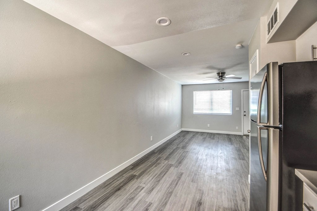 A kitchen with a black fridge and wooden floors.