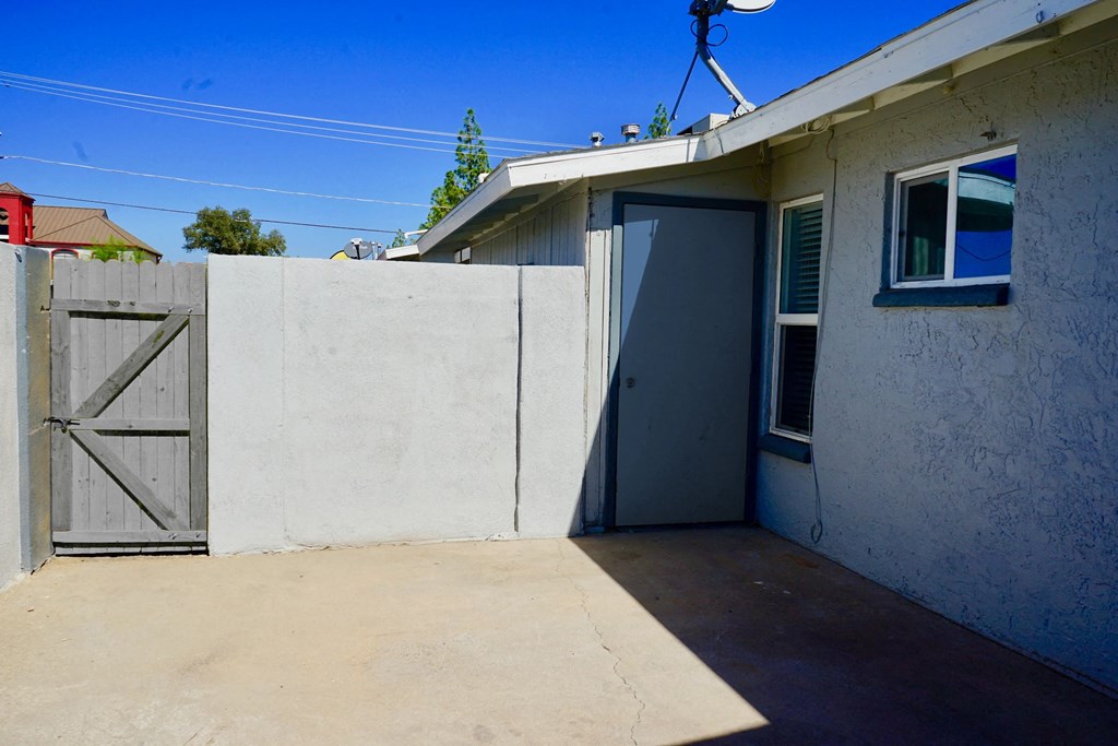 A concrete wall with a grey door and a window.