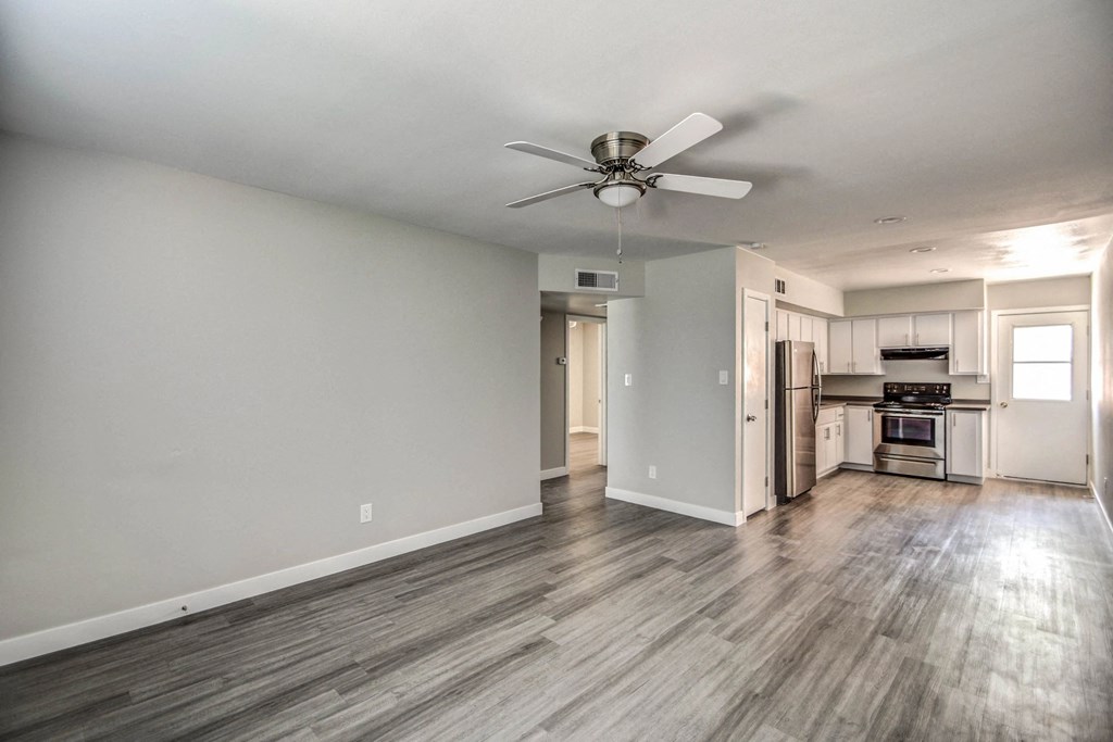 A spacious room with a ceiling fan and hardwood flooring.