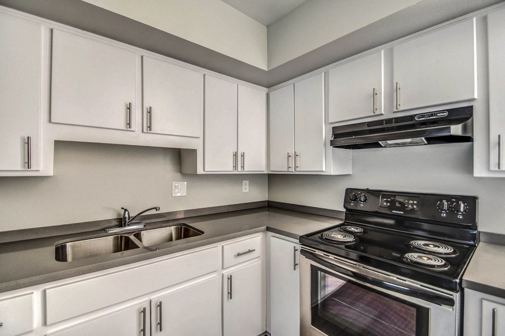 A kitchen with white cabinets and a black stove top oven.