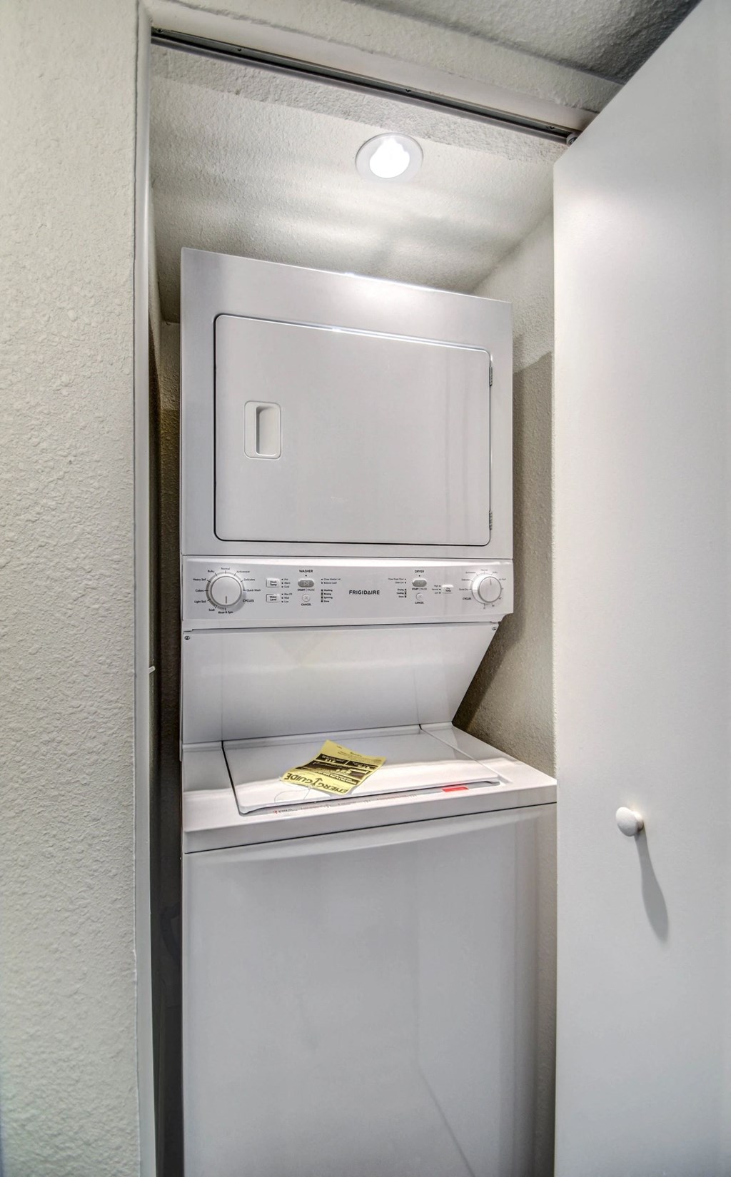 A white dishwasher is installed in a narrow space between a wall and a door.