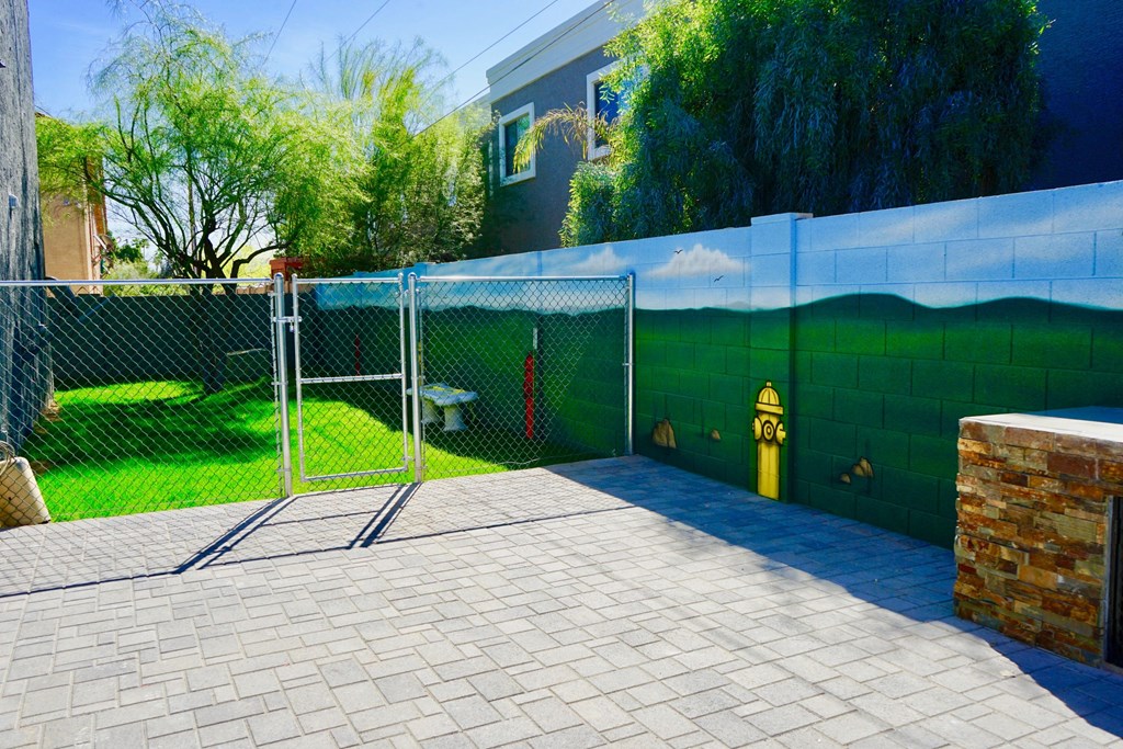 A fenced yard with a blue wall and a yellow fire hydrant.
