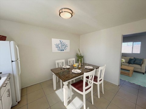 A kitchen with a table set for two with a plant on it.