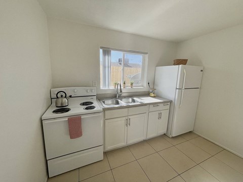 A small kitchen with white appliances and a window.