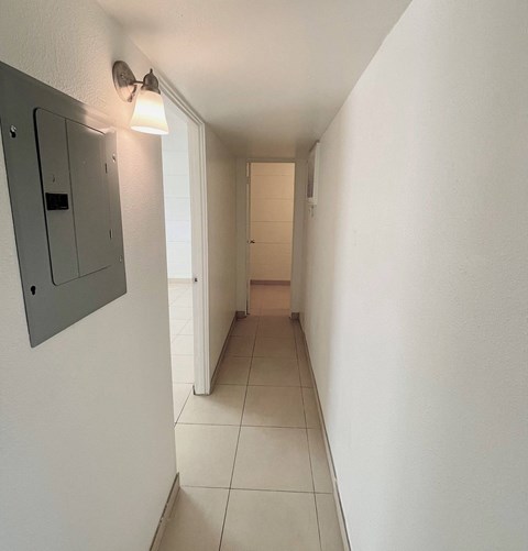 A long hallway with a light on the left and a door on the right.