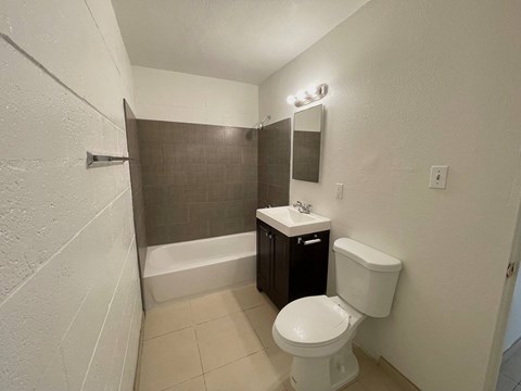 A small bathroom with a toilet, sink, and shower.