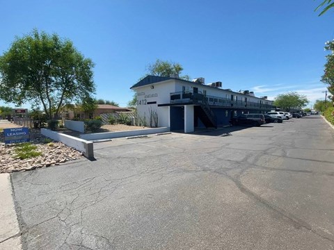 A parking lot with a building and a sign that says "NOW LEASING".