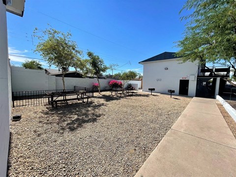 A gravel area with a bench and a building in the background.